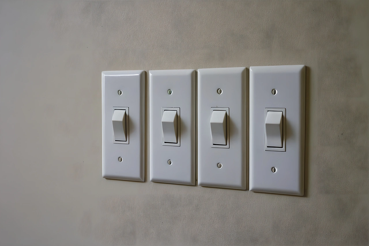 Row of four identical unlabelled light switch plates on a wall
